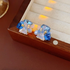 Macro detail of gold plated butterfly earrings with blue crystals on wooden box