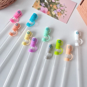 Flat lay of 10 colorful glass straws with daisy dust caps in various vibrant shades