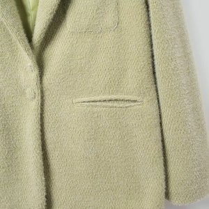 Detailweergave van de lichtgroene pluche textuur en zaknaad op de casual blazer