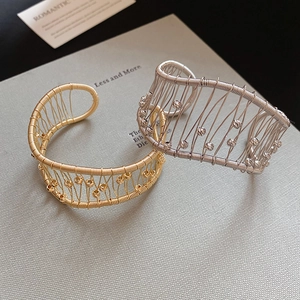 Detail of gold and silver woven hollow mesh bracelets with metallic bead accents