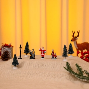 Miniature Christmas village set with Santa figurines and pine trees on snowy fabric