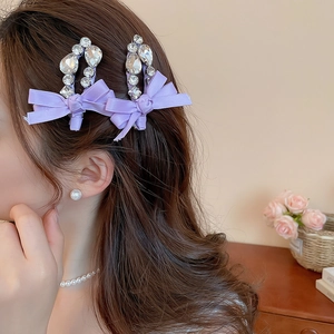 Détail d'une pince à cheveux nœud en satin violet avec cristaux sur un mannequin