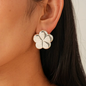 Close-up of a silver polished five-petal flower earring on a female model ear