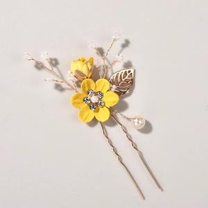 Macro view of bridal hair pin with handmade yellow fabric flower and gold metal leaf