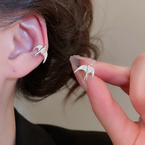 Detailed view of silver swallow ear cuff with cubic zirconia on a model ear