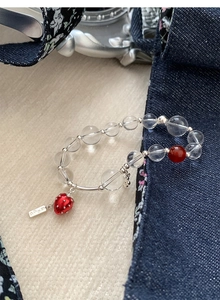 Detail of beaded strawberry bracelet with glass beads and silver 'Dream' tag