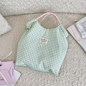 Dettaglio della borsa shopper a quadri verdi con manico in corda intrecciata rosa