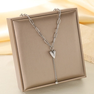 Détail du pendentif cœur avec chaîne trombone et frange sur de la soie élégante