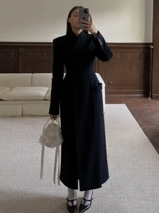 Selfie miroir d'un long manteau noir cintré porté avec un sac élégant à perles blanches