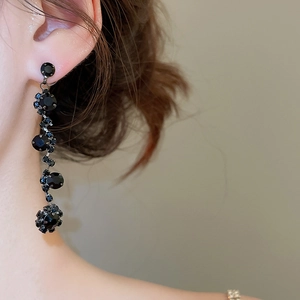 Close-up of elegant black rhinestone long drop earrings worn on a female model