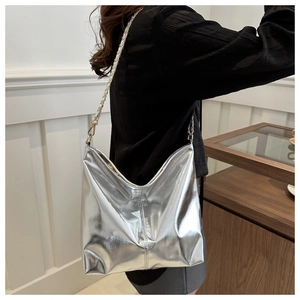 Close-up of silver chain strap and metallic pleated bucket bag worn by a model