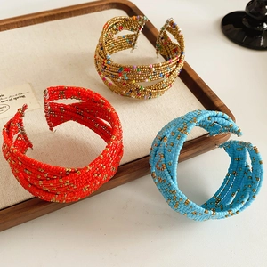 Détail de bracelets bohèmes multicouches en perles de verre aux motifs rouge et doré