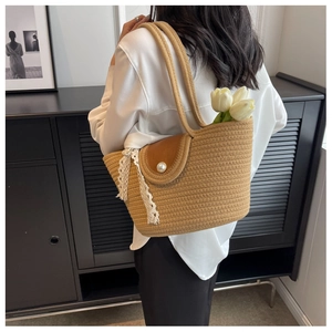 Detail of straw woven tote with leather flap, pearl button, and delicate lace trim detail