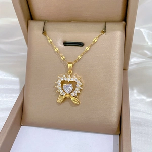 Macro view of gold heart pendant with sparkling crystals and bow detail on fine chain