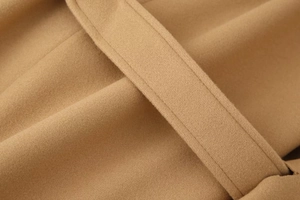 Macro shot of camel wool coat fabric texture featuring precise stitching and belt loop