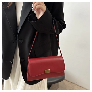 Minimalist red leather baguette shoulder bag featuring a sleek gold metallic clasp