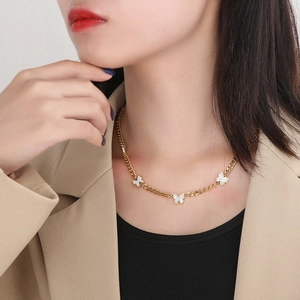 Close-up of golden necklace featuring three white shell butterfly charms on NK chain
