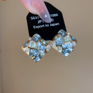Detail view of geometric square stud earrings with mosaic blue tiles and zircon inlays
