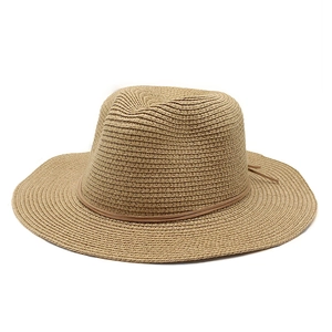 Detailed close-up of woven straw fedora texture with slim leather band decoration
