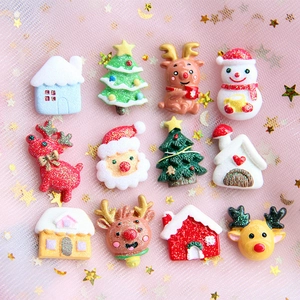 Flat lay of 12 resin Christmas charms including Santa and reindeer on pink starry mesh