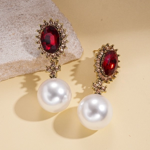 Luxury oval red ruby earrings with white pearls and gold accents on grey stone background