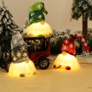 Tre gnomi di Natale luminosi con barbe a luce calda e cappelli in maglia con fiocchi