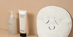 Close-up of a white facial towel mask with precise eye and mouth cutouts for skincare