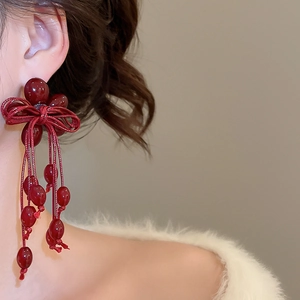 Detail of red beaded bow tassel earrings with a vintage-inspired berry cluster design