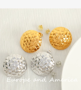 Detailed view of large round gold and silver earrings with woven embossed texture finish