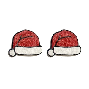 Close-up of red and white embroidered Christmas hat earrings with detailed fabric texture