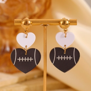 Détail de boucles d'oreilles en cœur avec motif de rugby marron sur un support doré
