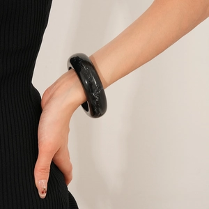 Detailed view of thick black marble texture resin bangle on a woman's wrist