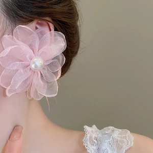 Detail of pink chiffon flower earring with pearl center on model for styling