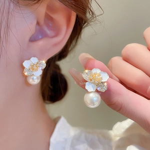 Elegant gold flower earrings with zircon petals and a round pearl drop on female model