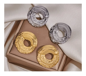 Detail of round earrings featuring irregular hammer textures and radial gold and silver patterns