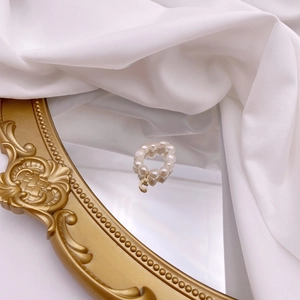 Macro detail of natural freshwater pearl ring with a golden letter C metal pendant charm