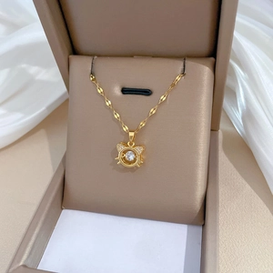 Close-up of golden cat pendant necklace with sparkling crystal inlay on silk background
