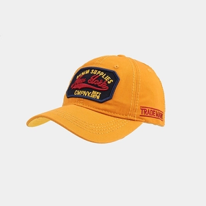 Detail view of orange baseball cap featuring vintage shield embroidery and side logo