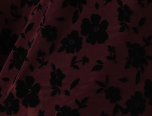 Detail of dark red mesh fabric with black flocked floral patterns on mini dress