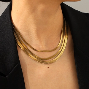 Detailed view of layered 18k gold-plated stainless steel herringbone snake chains on model