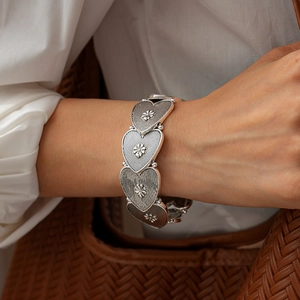 Detailed view of vintage silver heart-shaped links with floral relief and vertical stripes
