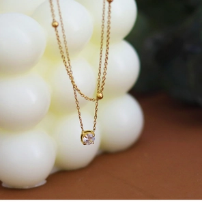 Detail of double-layer gold chain necklace with cubic zirconia pendant and beads