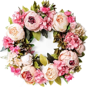 Macro detail of artificial pink peony and hydrangea wreath with realistic green leaves