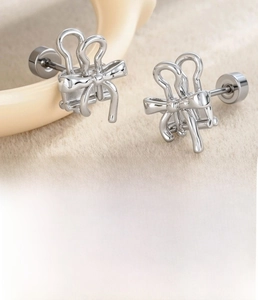 Detailed view of silver bow stud earrings in titanium steel with flat disc screw backs