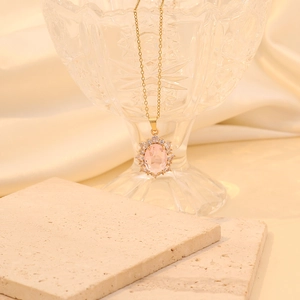 Detailed close-up of pink oval gemstone necklace with sparkling crystal halo on stone slab
