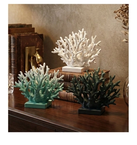 Detailed view of resin coral ornaments in white and green on a vintage wooden desk