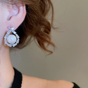 Macro view of crystal zircon and round pearl drop earring on model ear in high detail