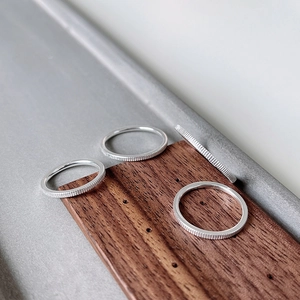 Detail of silver S925 rings with vertical ribbed texture on a wooden stand