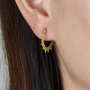 Gold-plated C-shaped hoop earrings with unique textured spikes on a female model