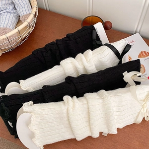 Detail of rib-knit leg warmers in black and beige with silk satin bow accents